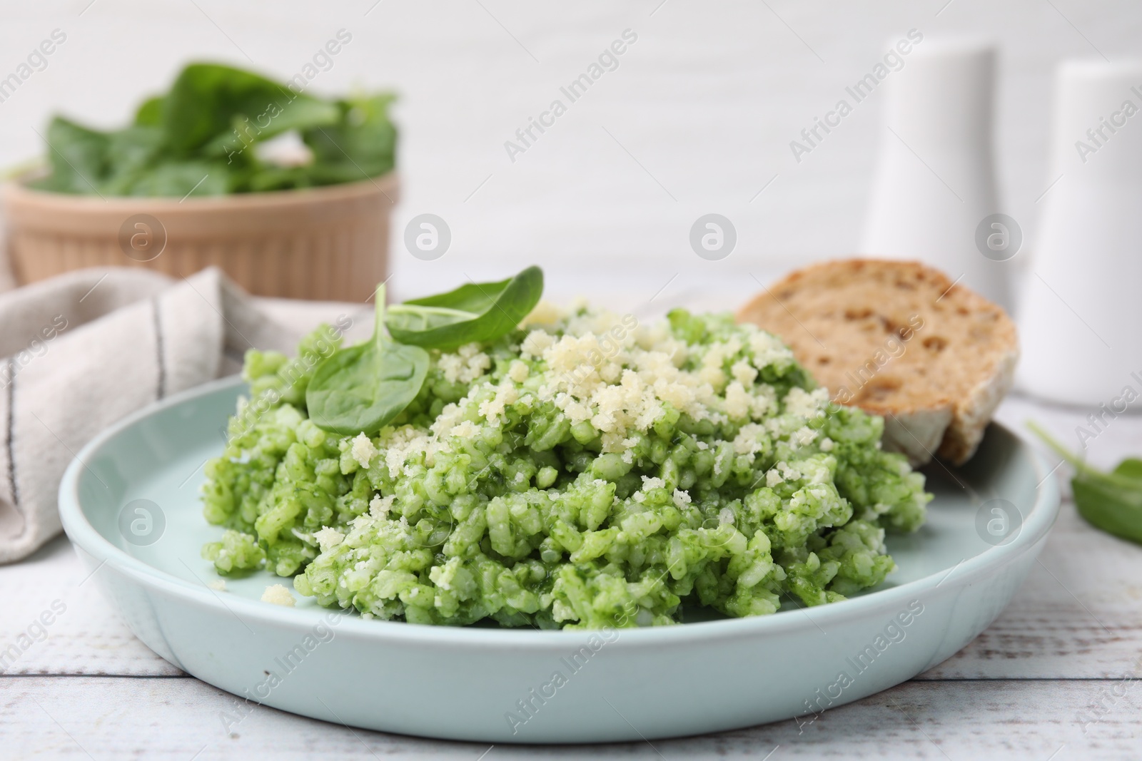 Photo of Tasty spinach risotto served with bread on white wooden table, closeup