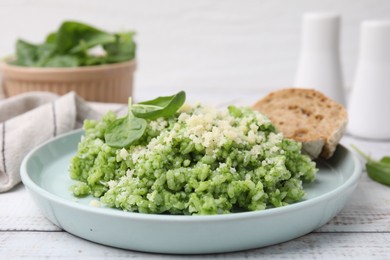 Photo of Tasty spinach risotto served with bread on white wooden table, closeup