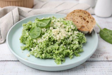 Photo of Tasty spinach risotto served with bread on white wooden table, closeup