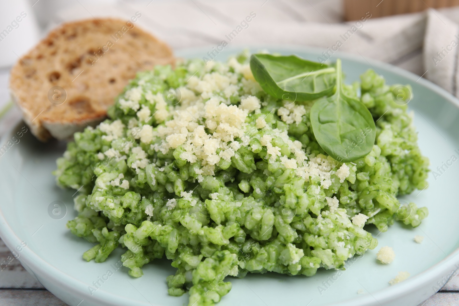 Photo of Tasty spinach risotto served with bread on white wooden table, closeup