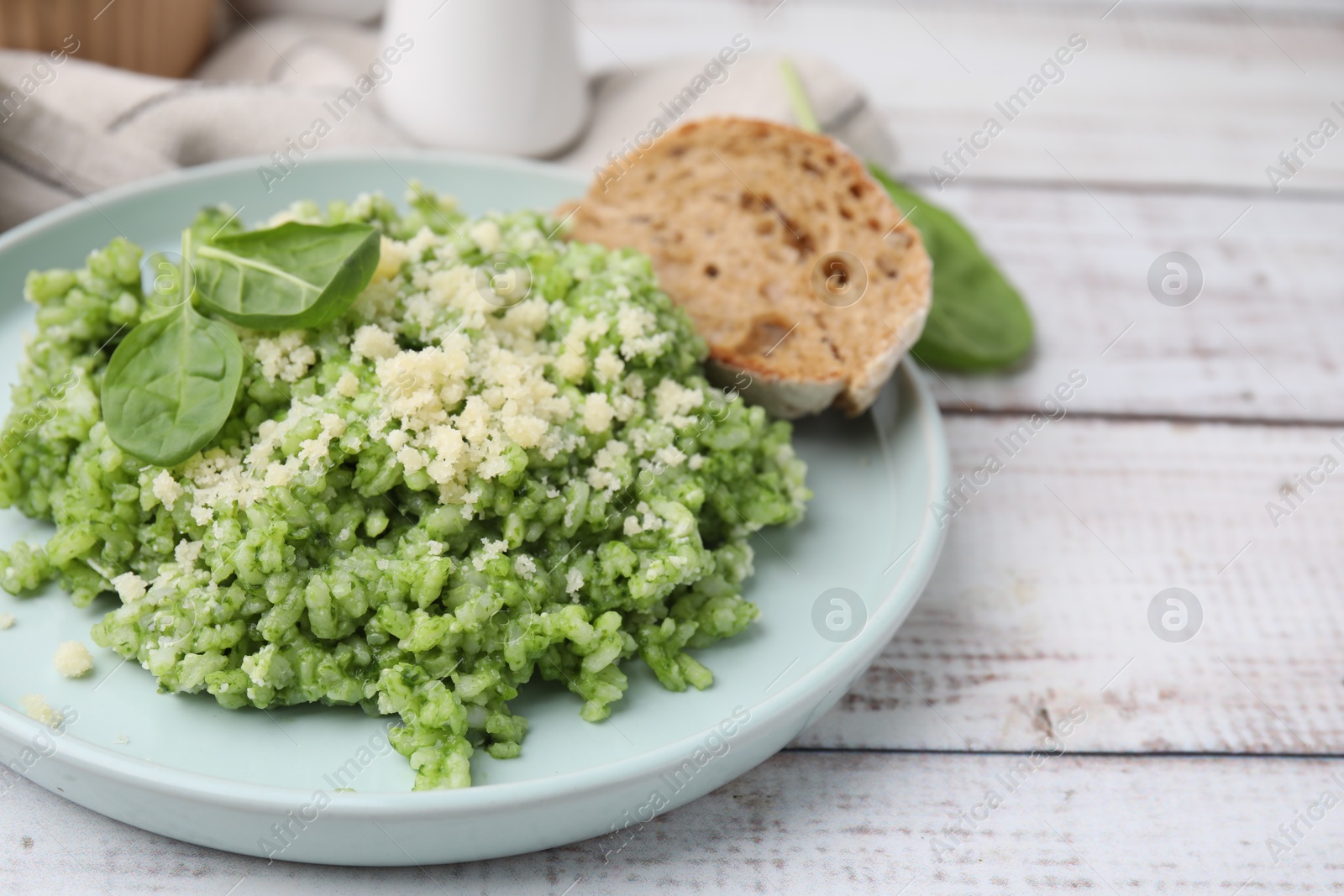 Photo of Tasty spinach risotto served with bread on white wooden table, closeup