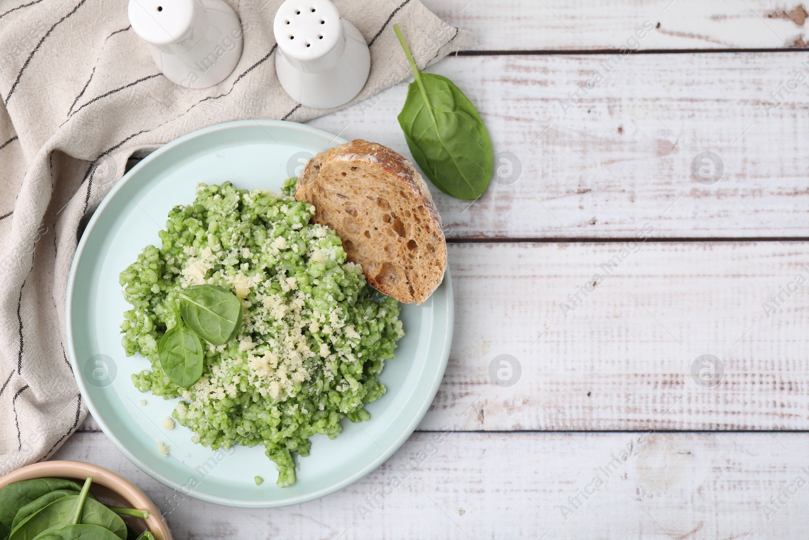 Photo of Tasty spinach risotto served with bread on white wooden table, flat lay. Space for text