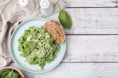 Photo of Tasty spinach risotto served with bread on white wooden table, flat lay. Space for text