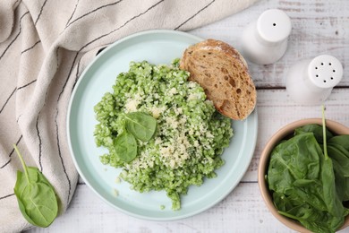 Photo of Tasty spinach risotto served with bread on white wooden table, flat lay