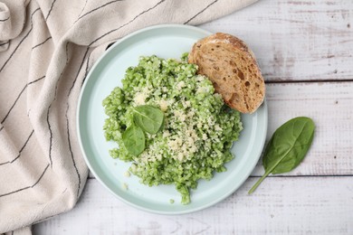 Photo of Tasty spinach risotto served with bread on white wooden table, top view