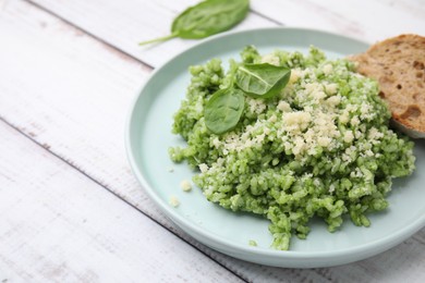 Photo of Tasty spinach risotto served with bread on white wooden table, closeup. Space for text