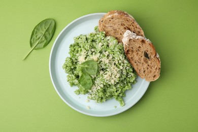 Photo of Tasty spinach risotto and bread on light green background, top view