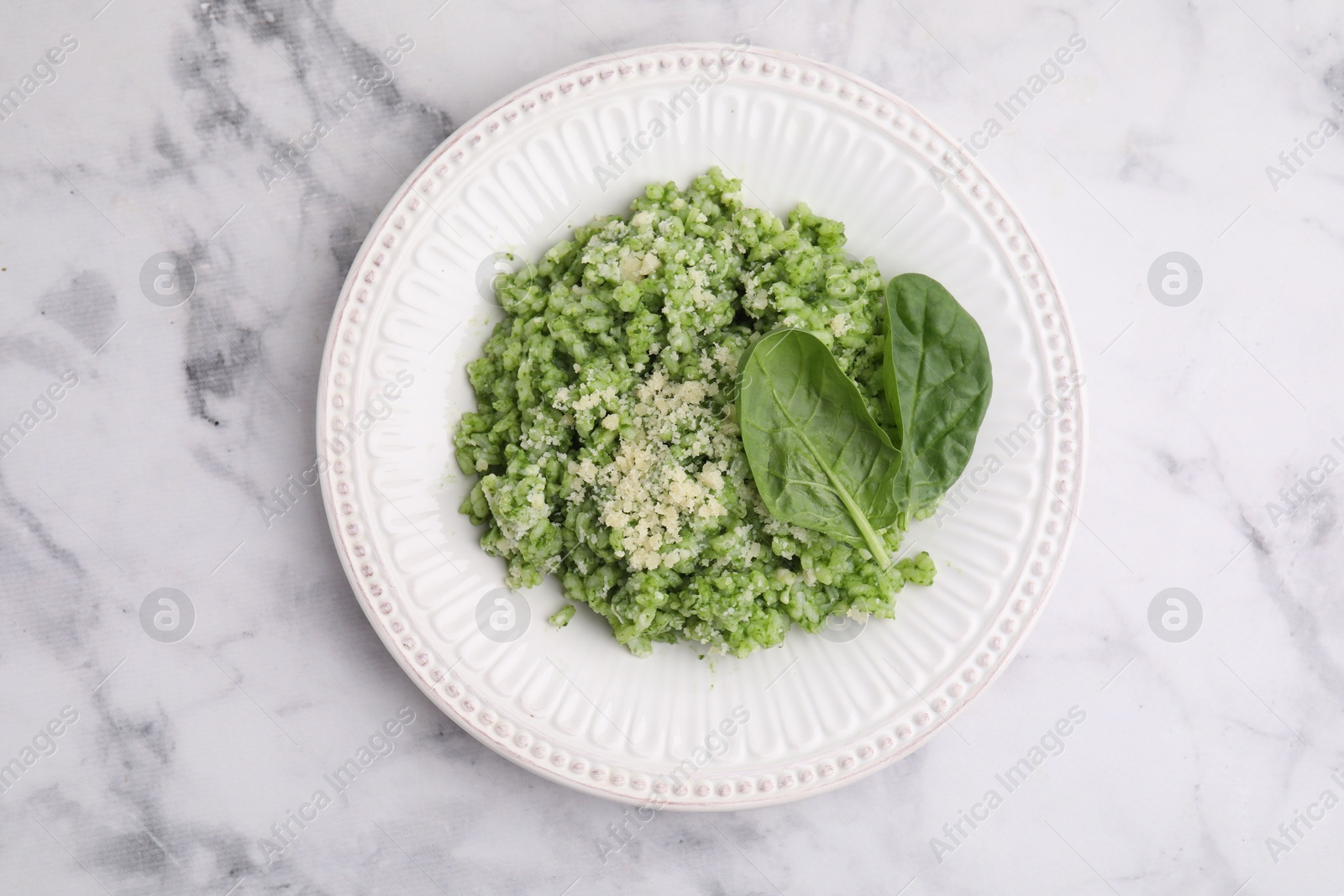 Photo of Tasty spinach risotto served on white marble table, top view