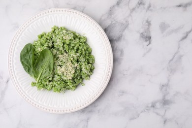 Photo of Tasty spinach risotto served on white marble table, top view. Space for text