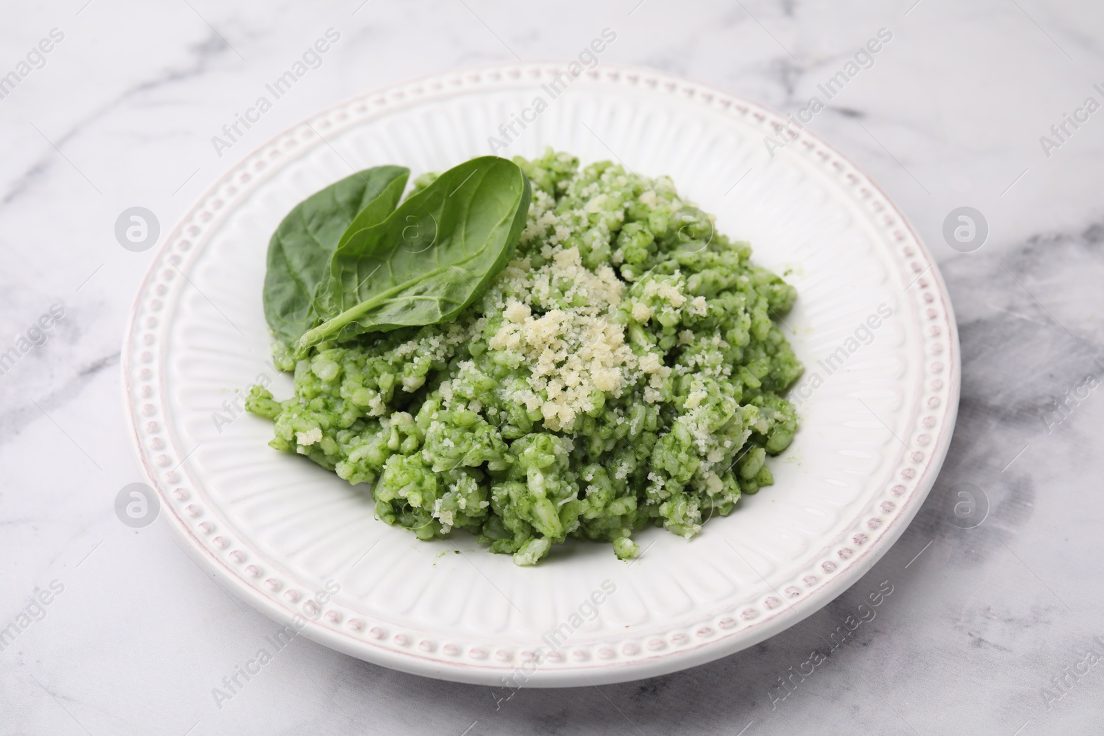 Photo of Tasty spinach risotto served on white marble table, closeup