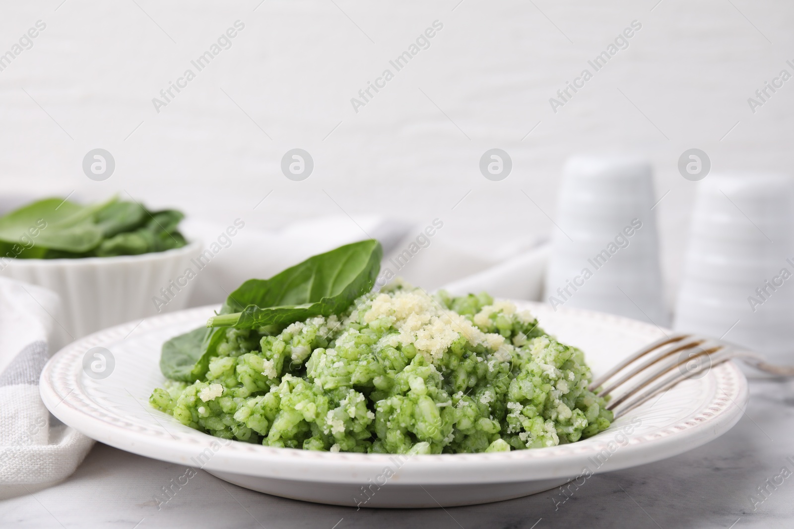 Photo of Tasty spinach risotto served on white marble table, closeup