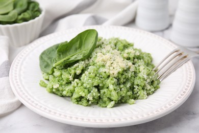 Photo of Tasty spinach risotto served on white marble table, closeup