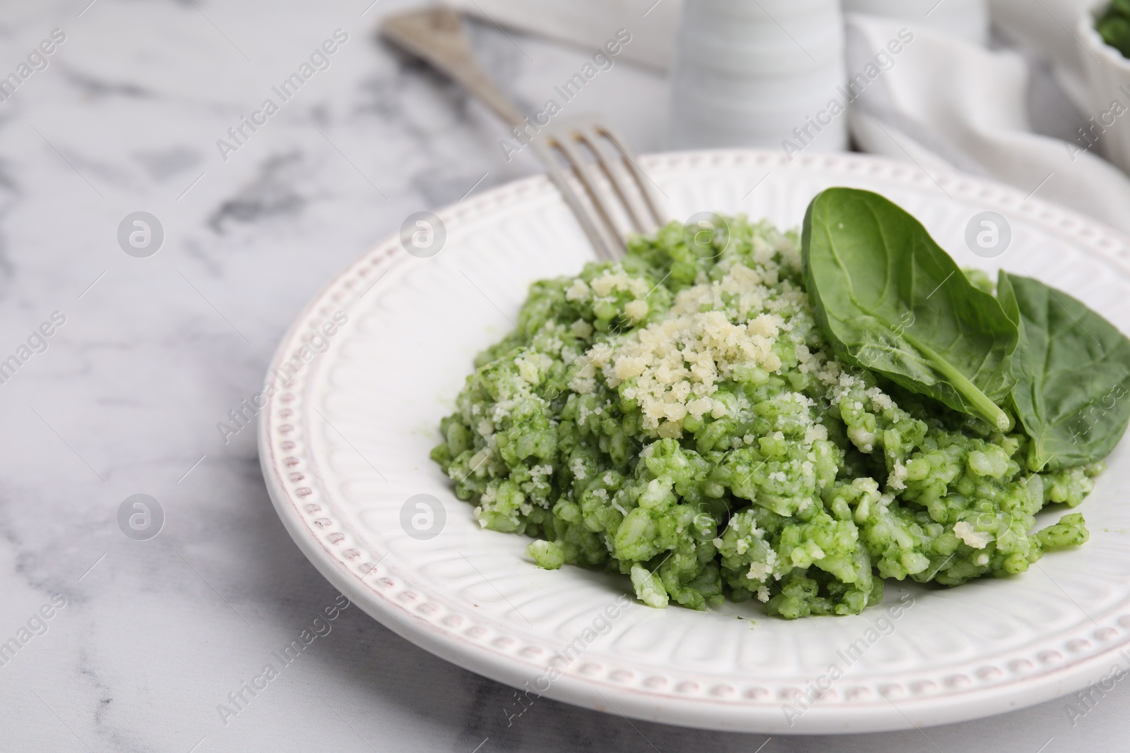 Photo of Tasty spinach risotto served on white marble table, closeup