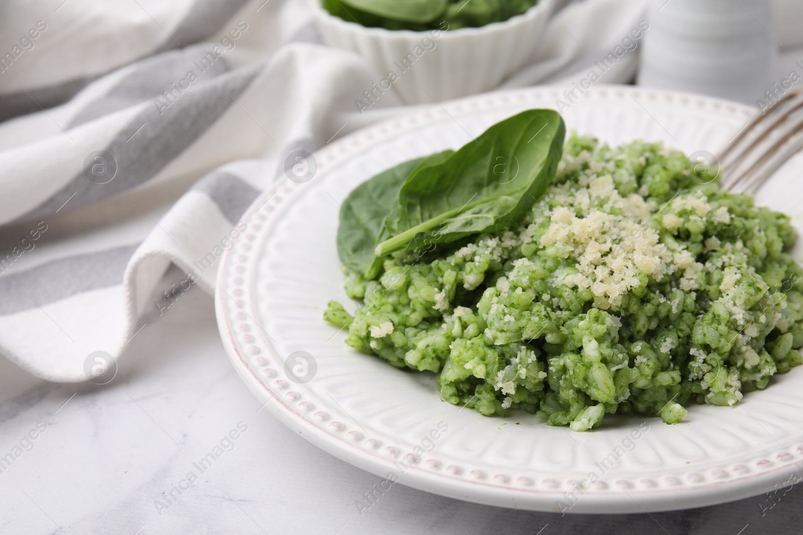 Photo of Tasty spinach risotto served on white marble table, closeup