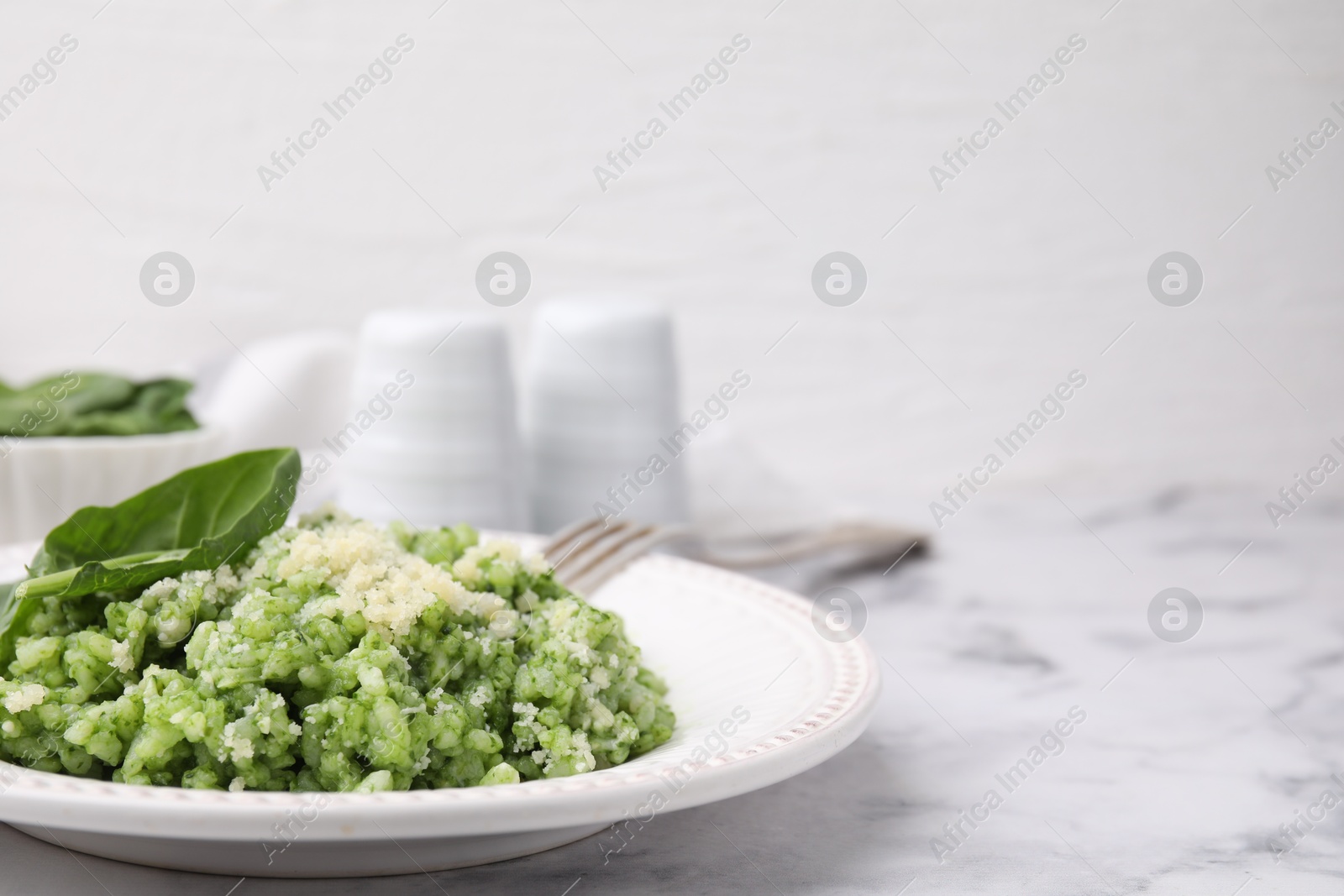 Photo of Tasty spinach risotto served on white marble table, closeup. Space for text