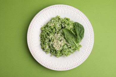 Photo of Tasty spinach risotto on light green background, top view