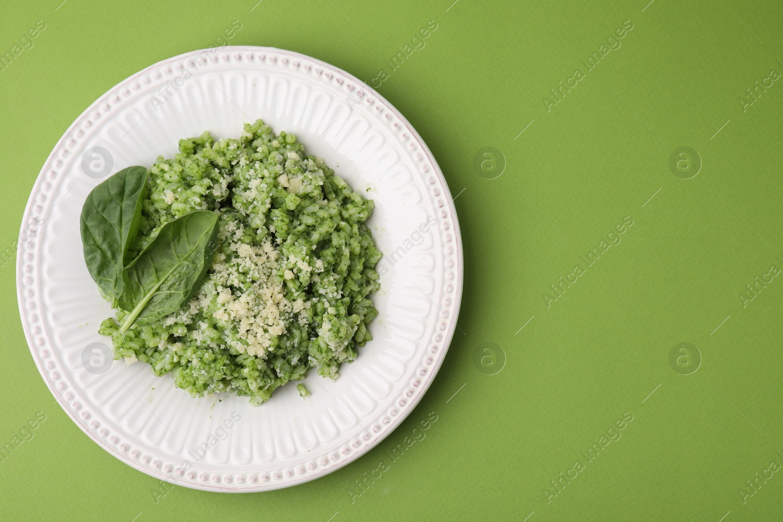 Photo of Tasty spinach risotto on light green background, top view. Space for text