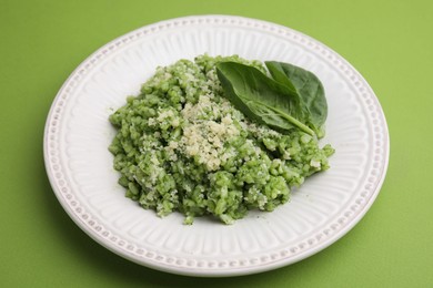 Photo of Tasty spinach risotto on light green background, closeup