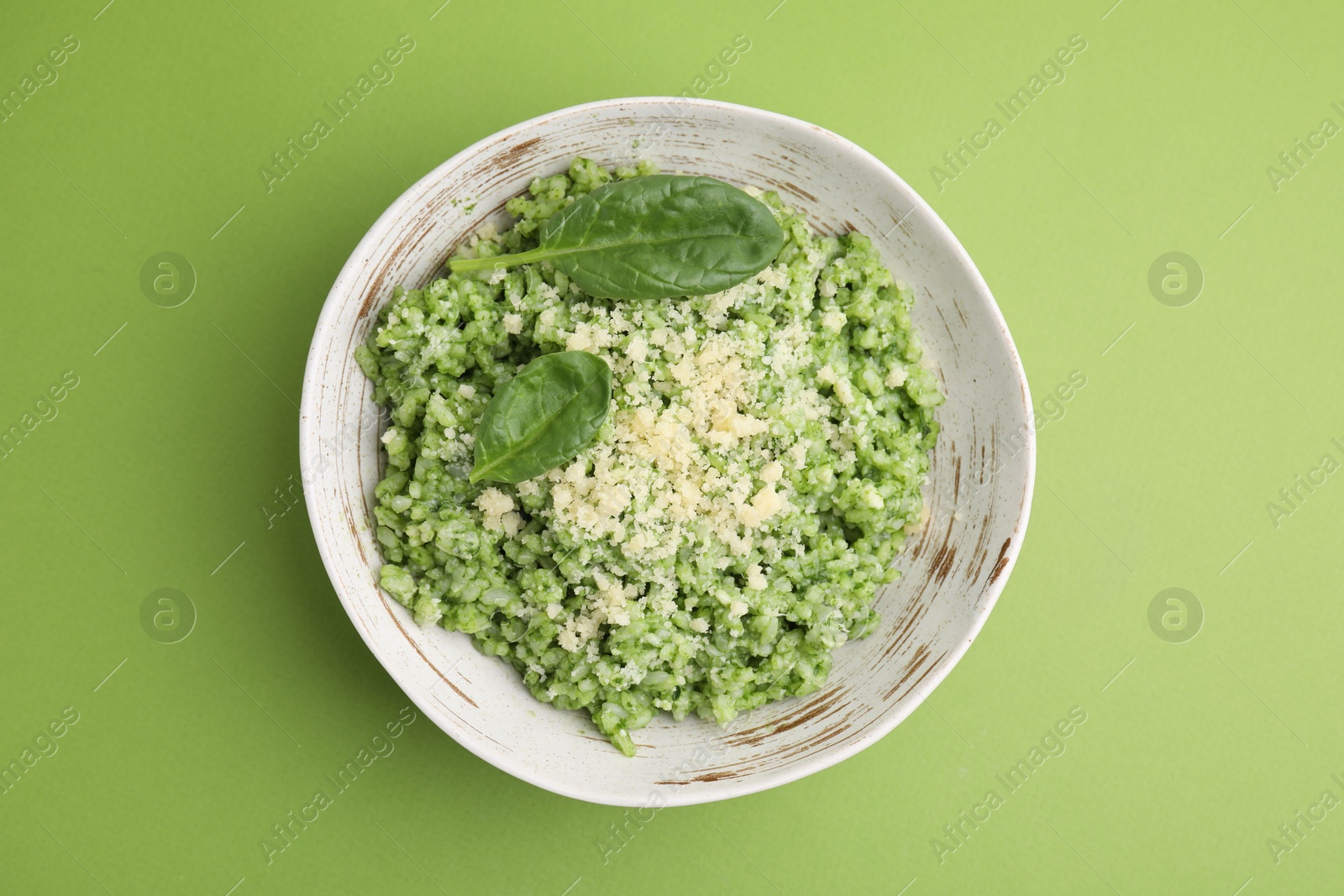 Photo of Tasty spinach risotto on light green background, top view