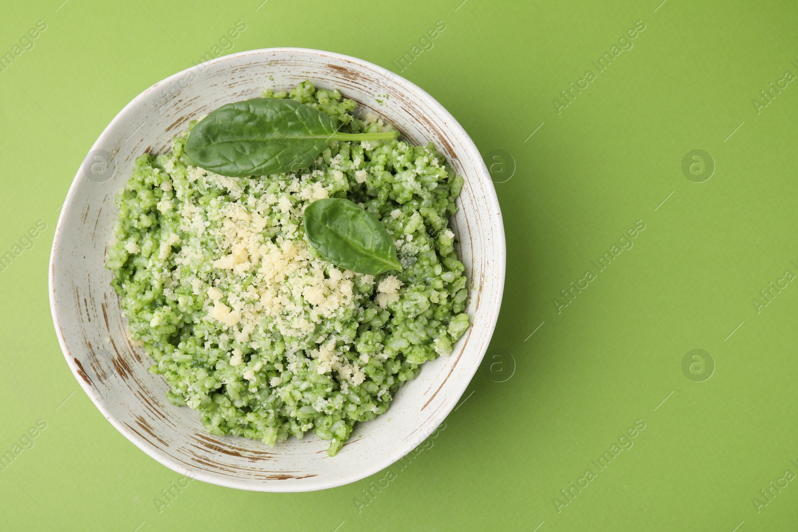 Photo of Tasty spinach risotto on light green background, top view. Space for text