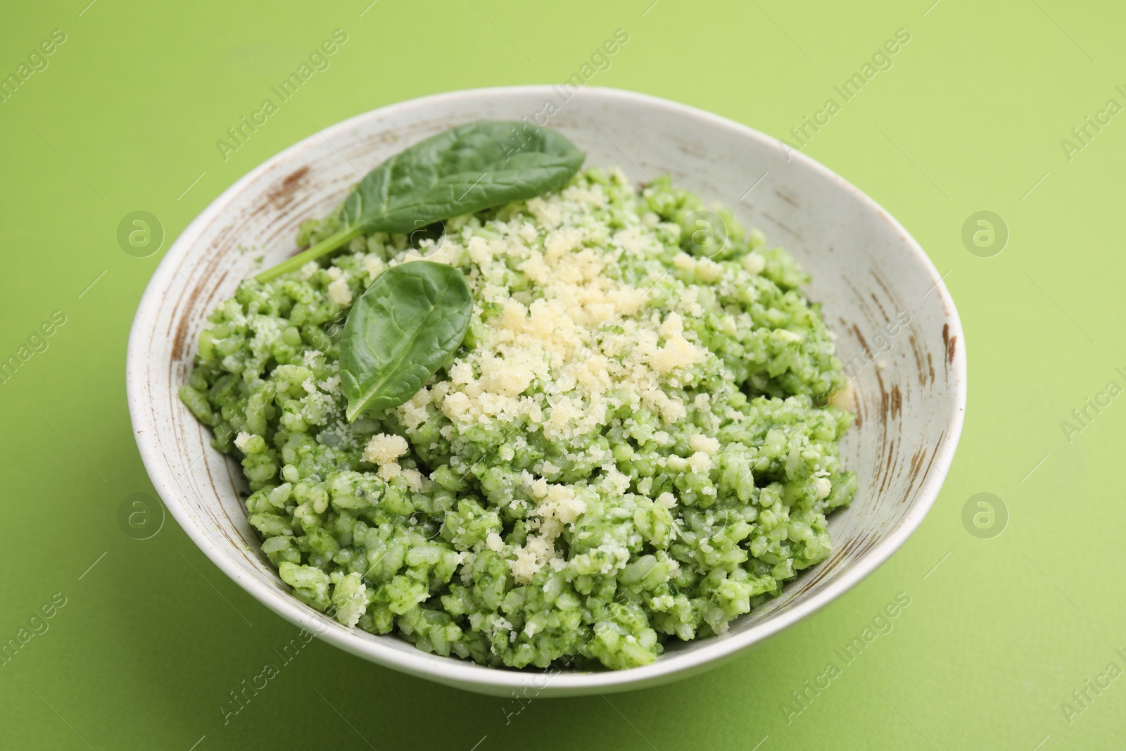 Photo of Tasty spinach risotto on light green background, closeup