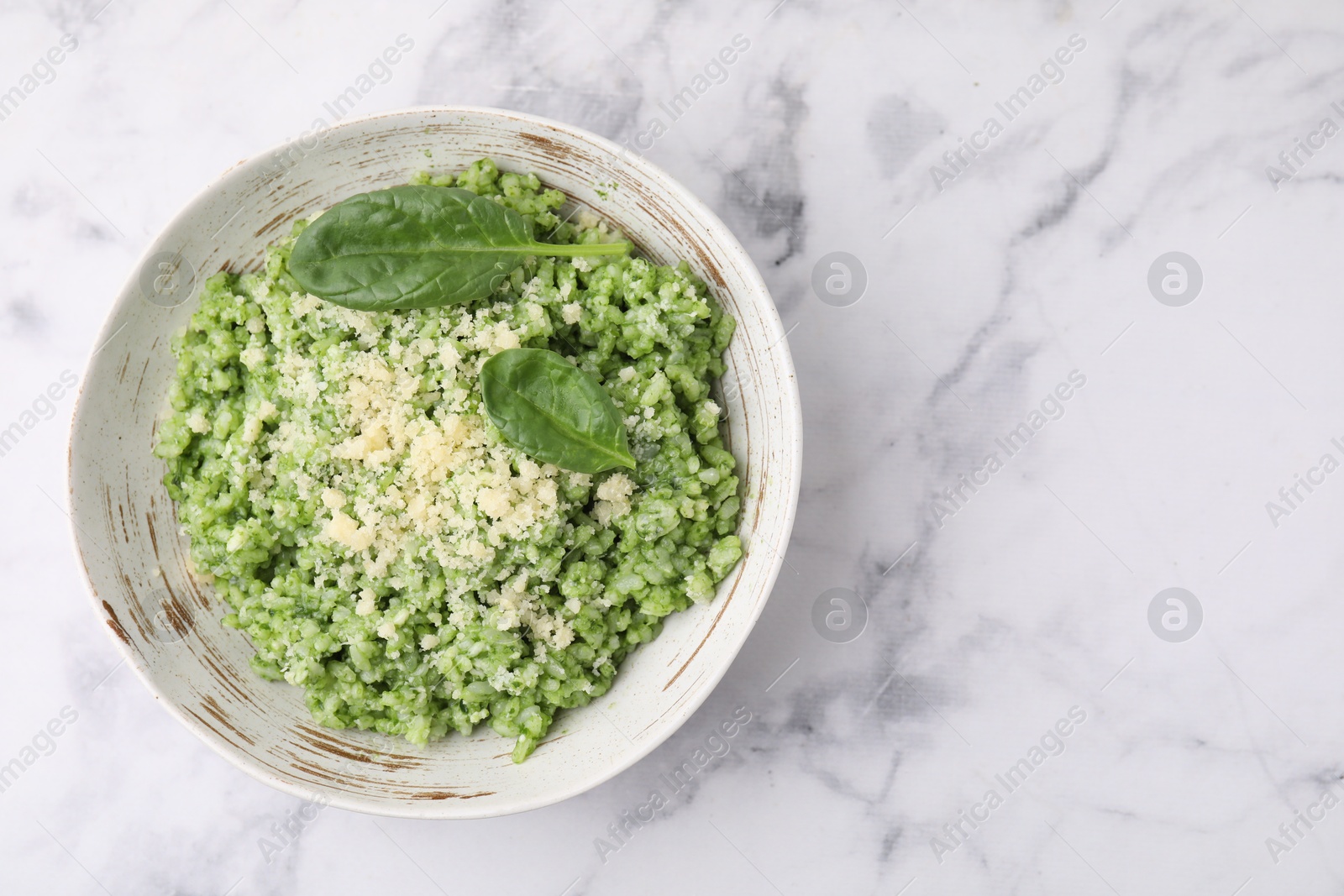 Photo of Tasty spinach risotto served on white marble table, top view. Space for text