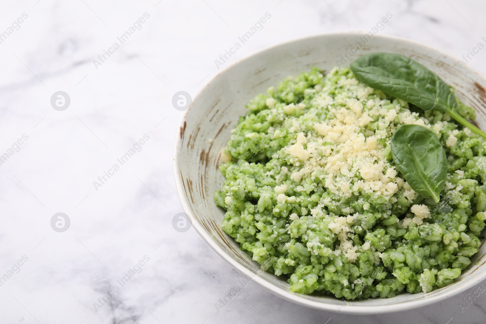 Photo of Tasty spinach risotto served on white marble table, closeup. Space for text