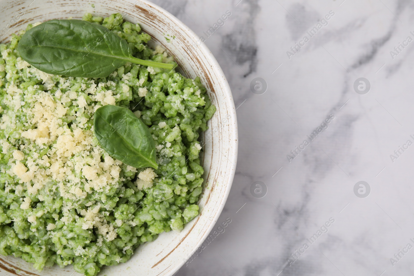 Photo of Tasty spinach risotto served on white marble table, top view. Space for text