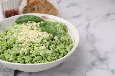 Photo of Tasty spinach risotto served on white marble table, closeup. Space for text