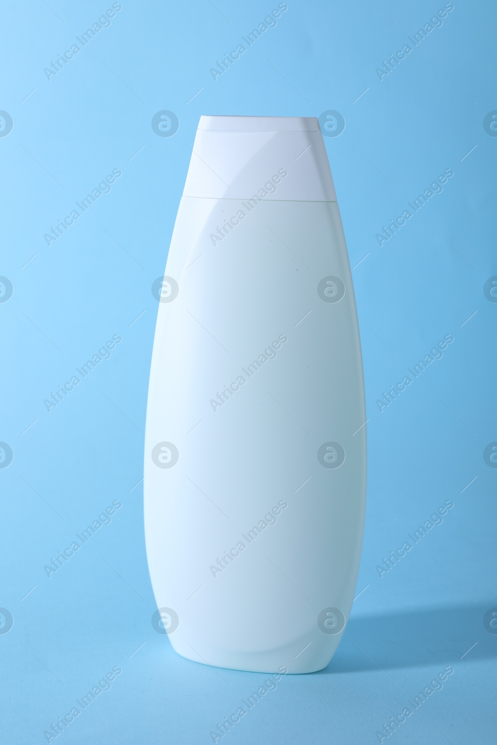 Photo of Shampoo in container on light blue background. Personal care product