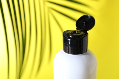 Photo of Shampoo in bottle on yellow background, closeup. Space for text