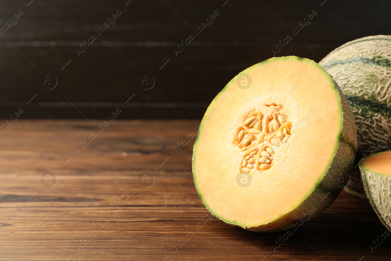 Photo of Cut Cantaloupe melon on wooden table, space for text