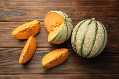 Cut and whole Cantaloupe melons on wooden table, flat lay