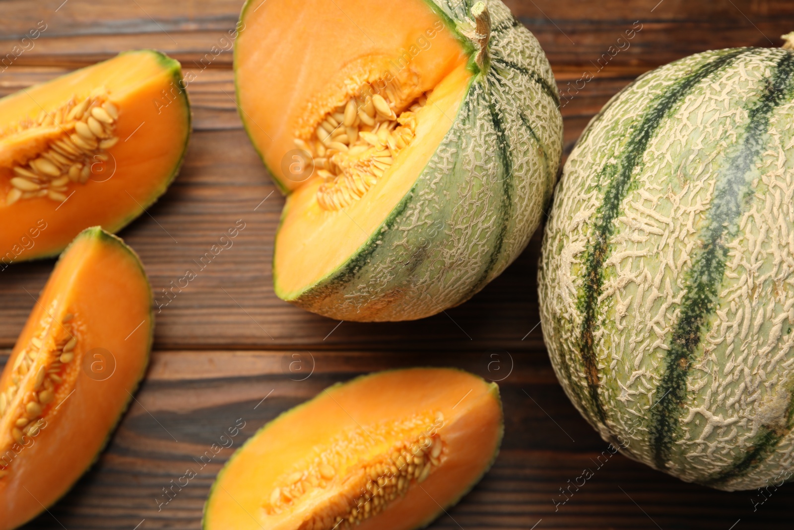 Photo of Cut and whole Cantaloupe melons on wooden table, flat lay