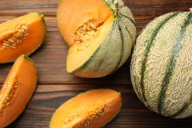 Cut and whole Cantaloupe melons on wooden table, flat lay