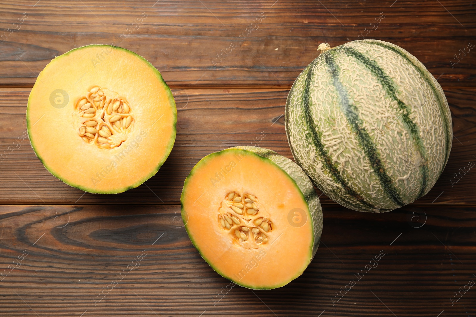 Photo of Cut and whole Cantaloupe melons on wooden table, flat lay