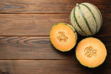 Cut and whole Cantaloupe melons on wooden table, flat lay. Space for text