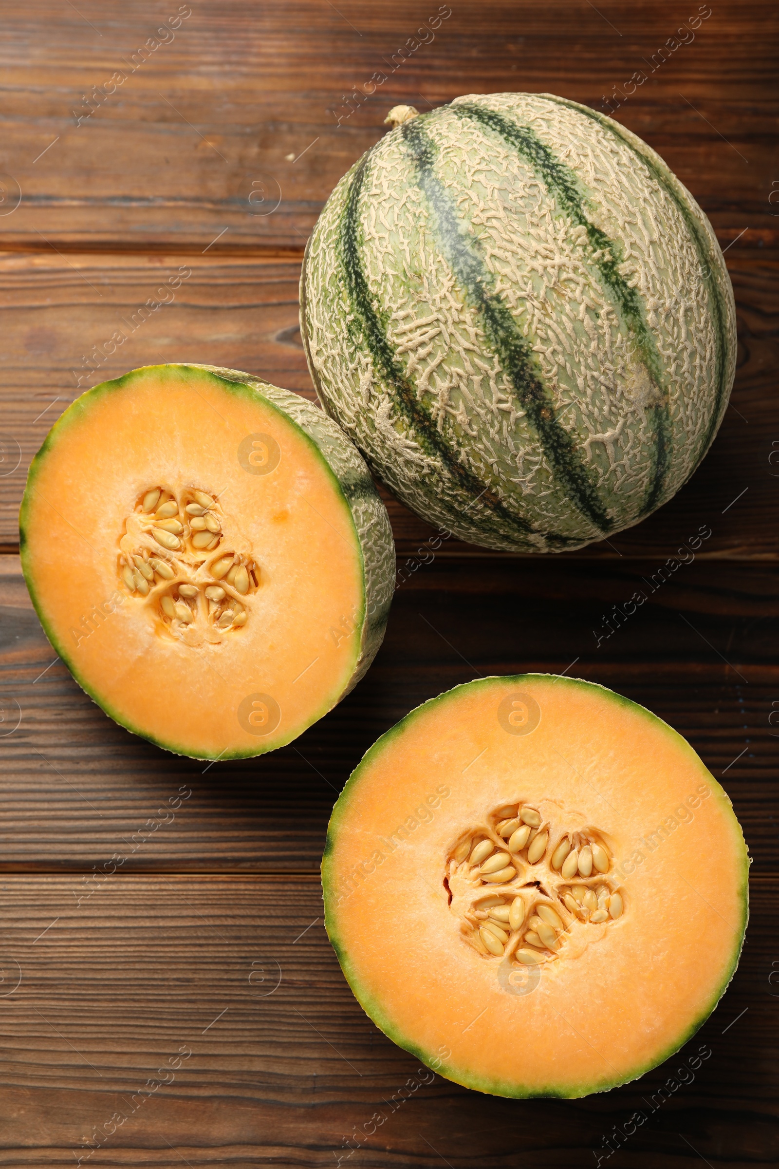 Photo of Cut and whole Cantaloupe melons on wooden table, flat lay