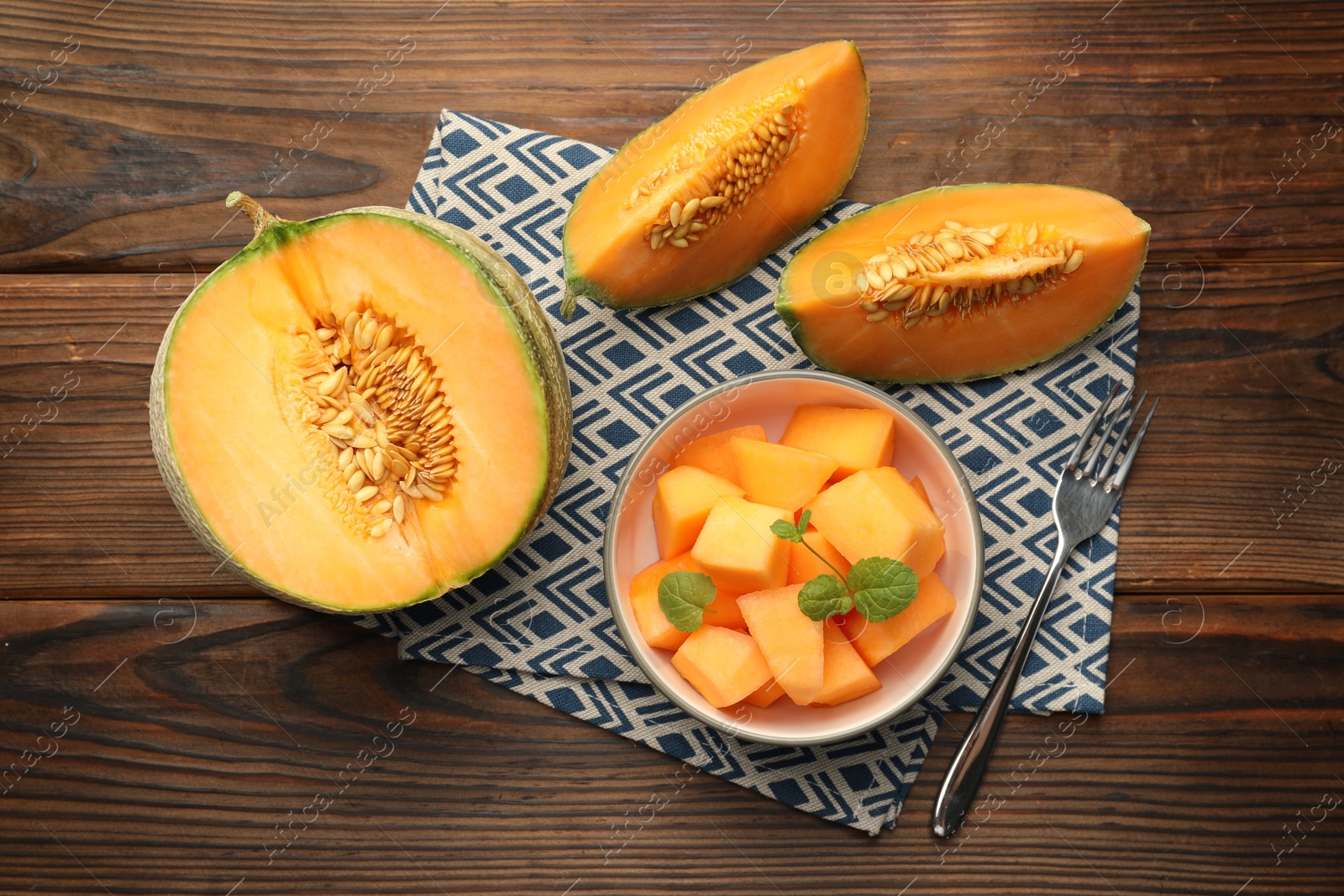 Photo of Tasty ripe Cantaloupe melons and fork on wooden table, flat lay