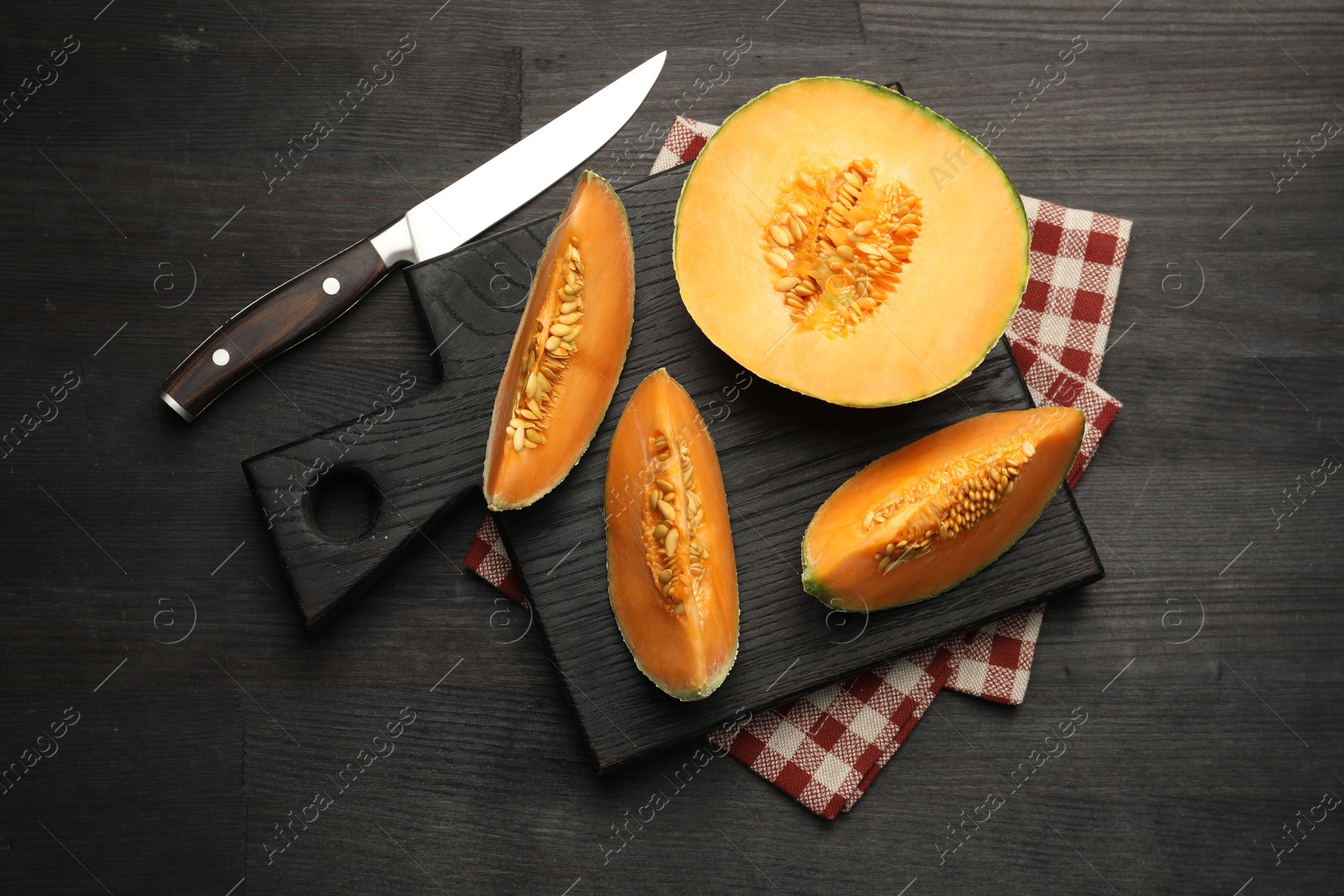 Photo of Fresh ripe Cantaloupe melon and knife on dark wooden table, flat lay