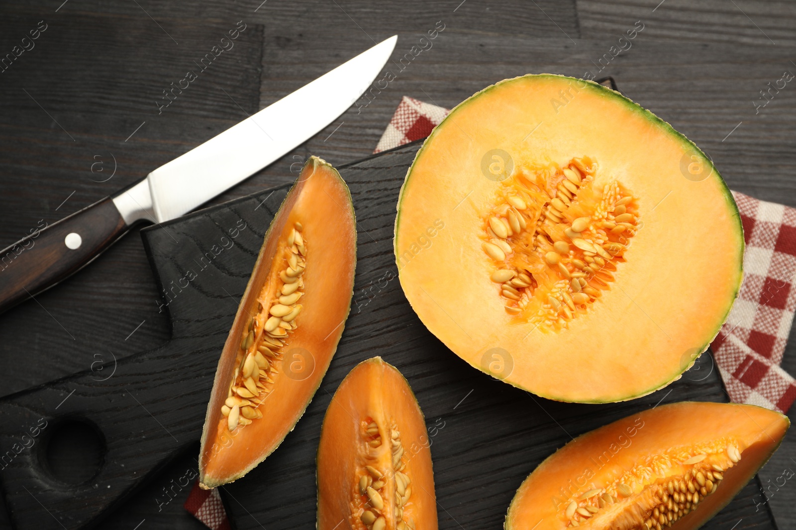 Photo of Fresh ripe Cantaloupe melon and knife on dark wooden table, flat lay