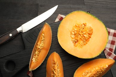 Photo of Fresh ripe Cantaloupe melon and knife on dark wooden table, flat lay