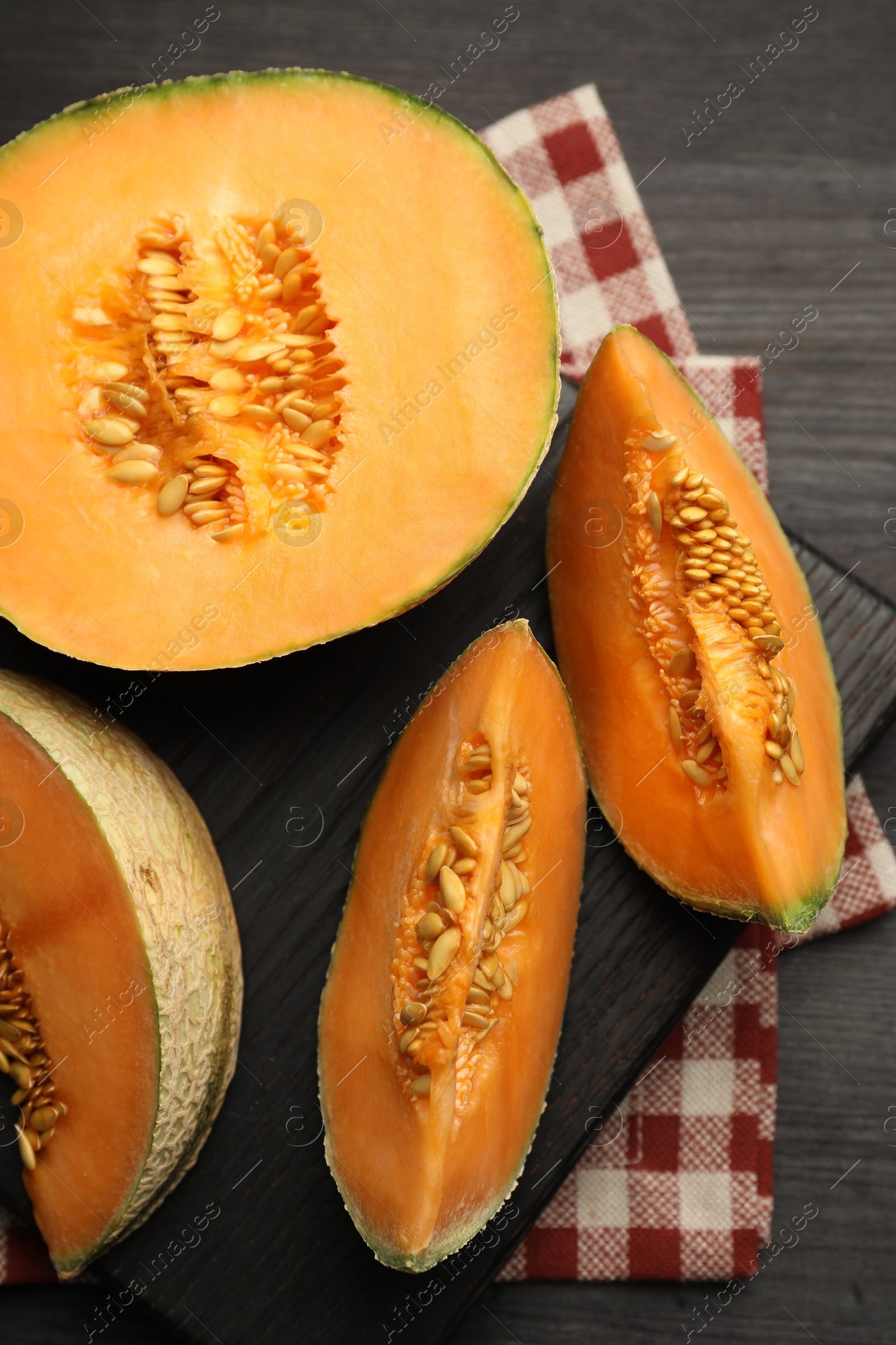 Photo of Fresh ripe Cantaloupe melon on dark wooden table, flat lay