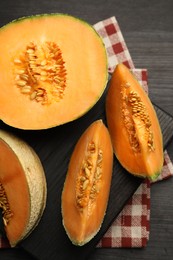 Photo of Fresh ripe Cantaloupe melon on dark wooden table, flat lay