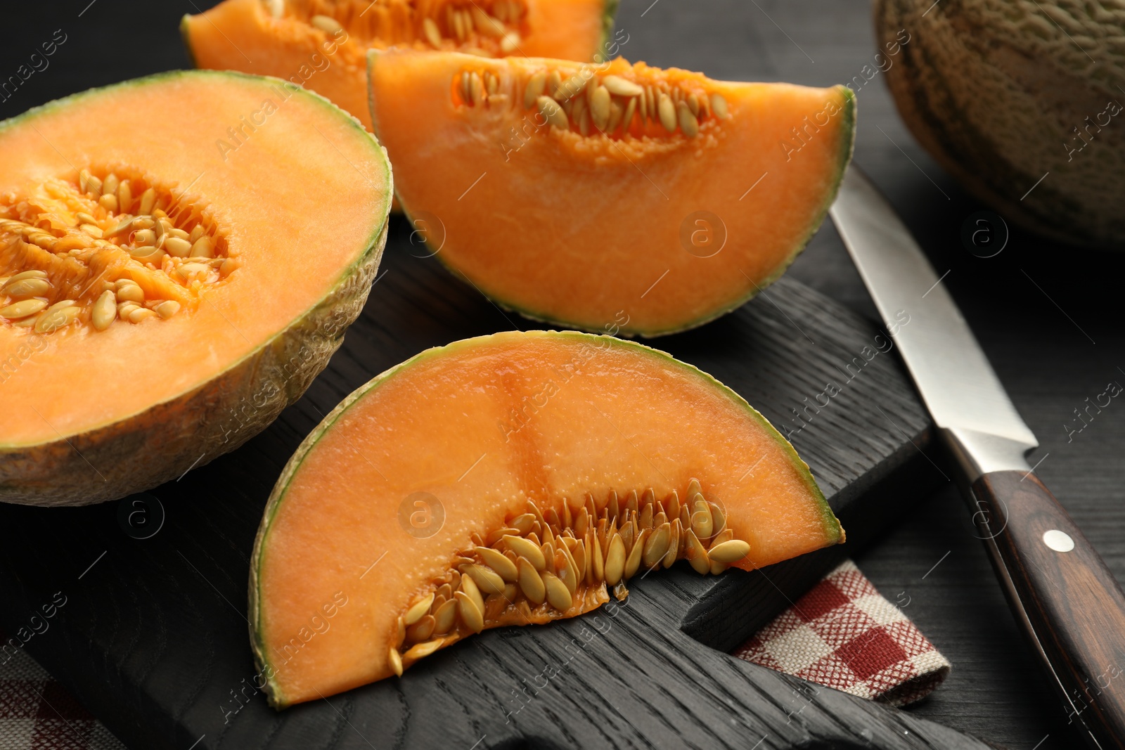 Photo of Fresh ripe Cantaloupe melon and knife on dark wooden table, closeup