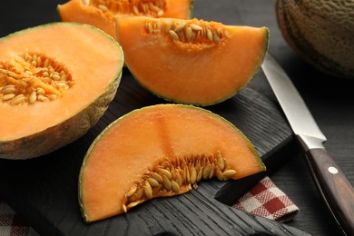 Photo of Fresh ripe Cantaloupe melon and knife on dark wooden table, closeup