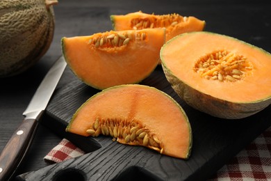 Photo of Fresh ripe Cantaloupe melon and knife on dark wooden table, closeup