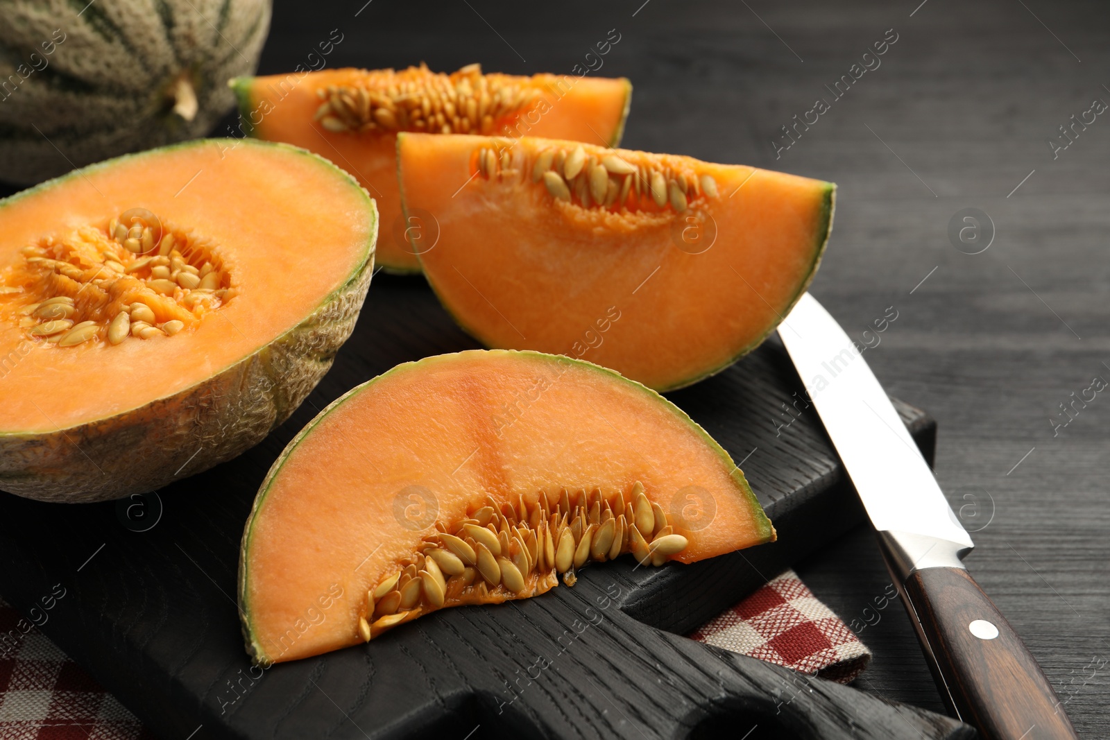 Photo of Fresh ripe Cantaloupe melons and knife on dark wooden table, closeup