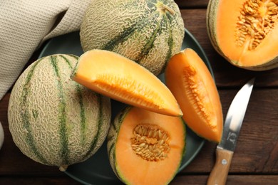 Photo of Fresh ripe Cantaloupe melons and knife on wooden table, flat lay