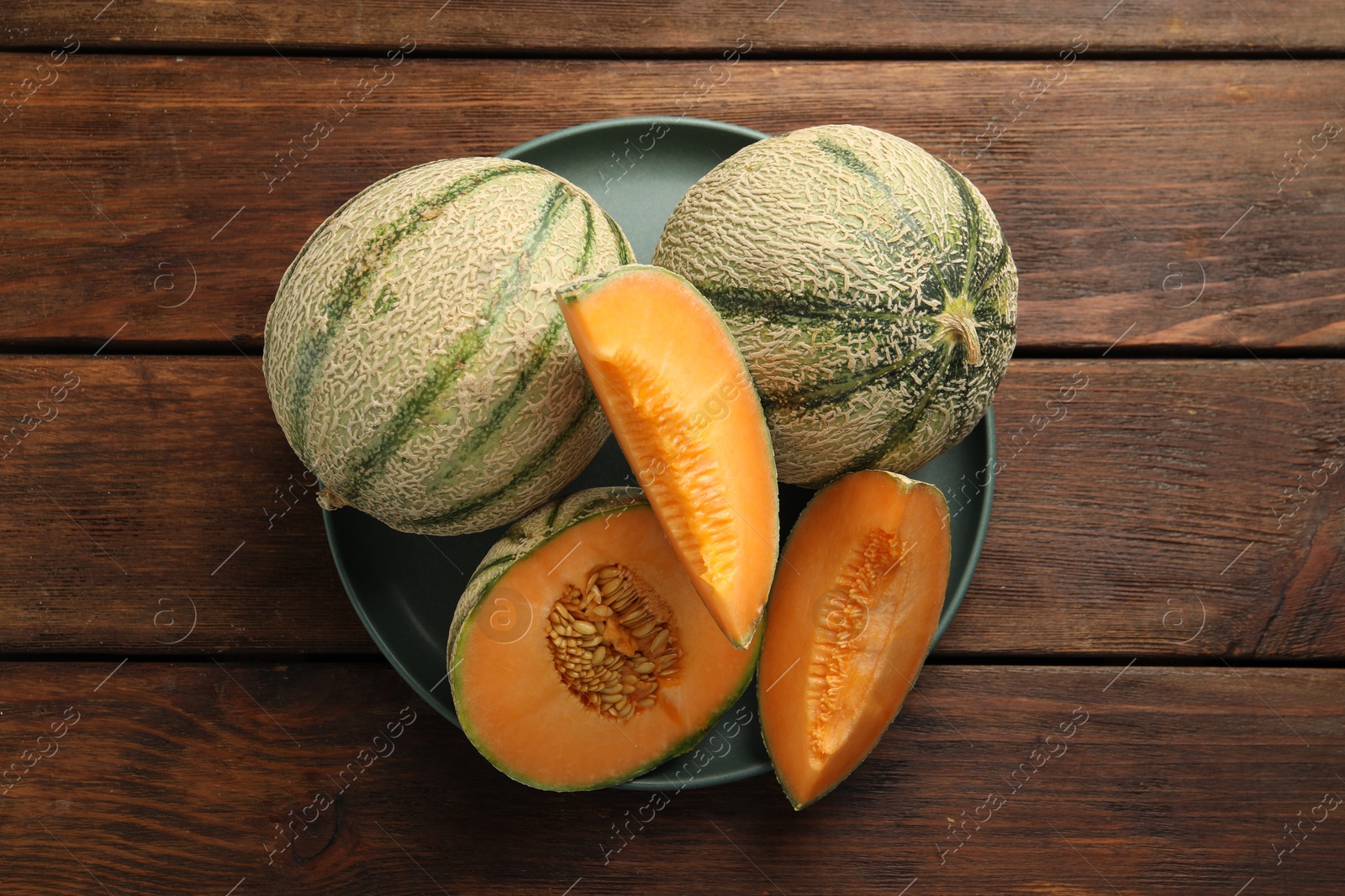 Photo of Fresh ripe Cantaloupe melons on wooden table, top view